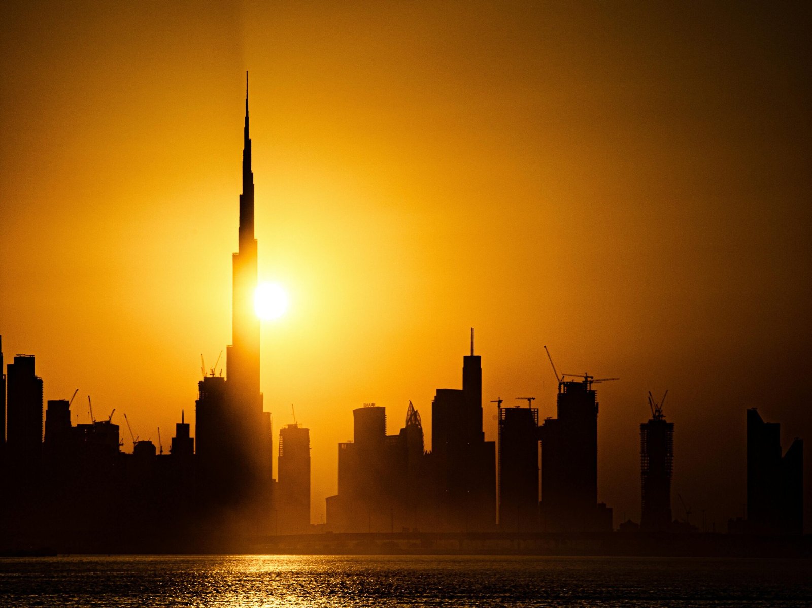 Stunning sunset view of Dubai skyline featuring the iconic Burj Khalifa silhouetted against the golden sky.
